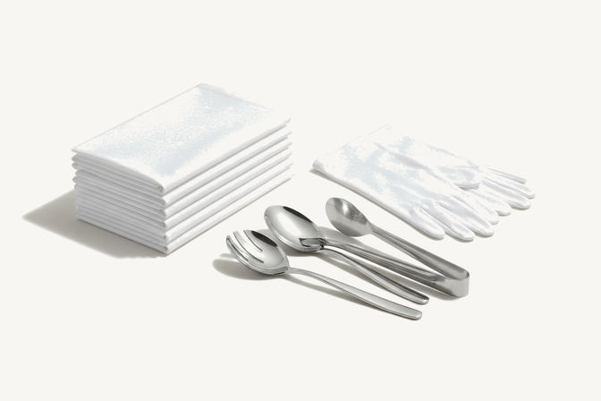 Folded white service napkins, white serving gloves and stainless serving spoons